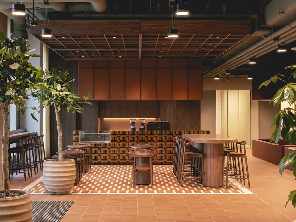 Coffee bar area with high stools around round wooden tables and a counter  