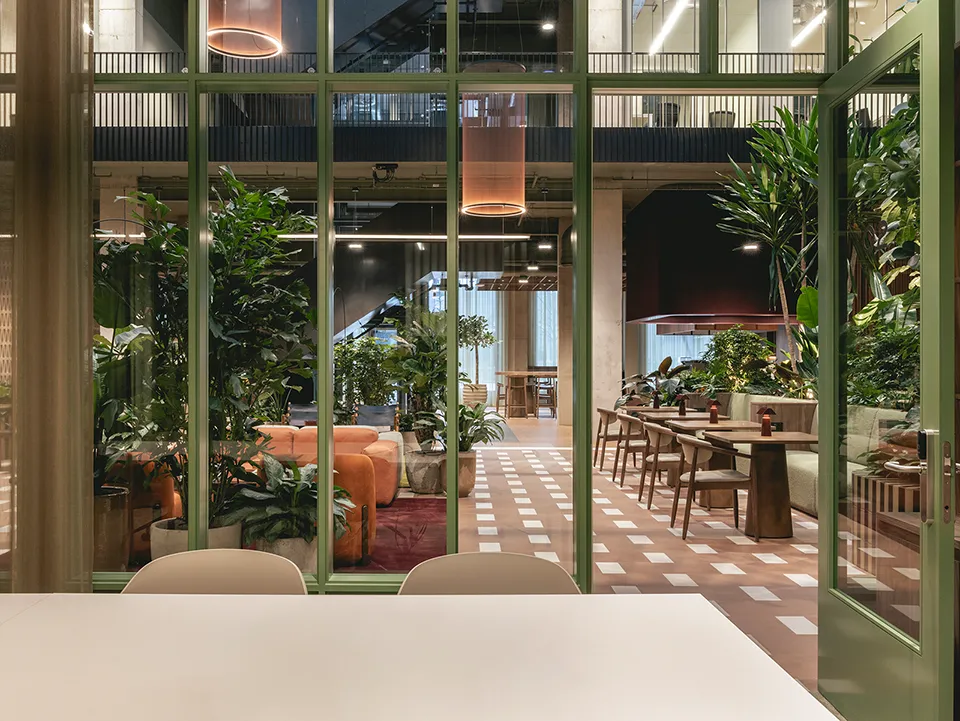 Inside a meeting room looking out through glass onto the atrium lounge and greenery