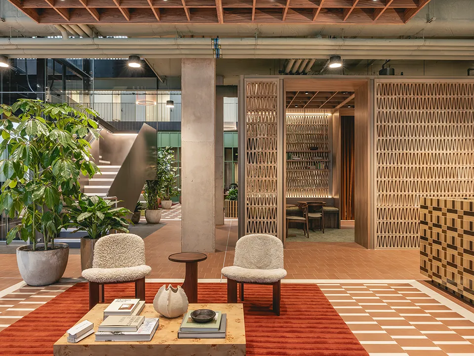 Two chair s in the reception area with a woven lattice screen and staircase beyond